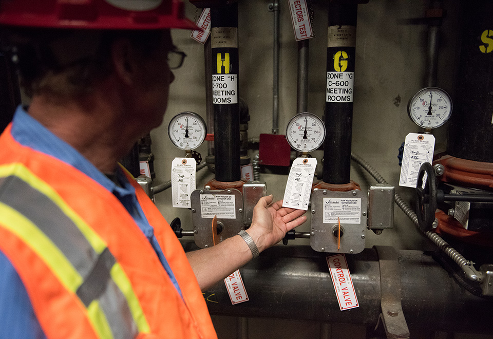 A coworker wearing safety gear checks control valves.